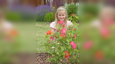 Die als Dornröschen verkleidete Henriette Scholz freut sich über die neu gepflanzten Gebrüder-Grimm-Rosen im Ludowinengarten und testet ihren Duft. Die Neunjährige wohnt direkt am Ludowinengarten und trifft sich dort oft mit ihren Freundinnen zum Spielen. (Foto: Bernhard Aufenanger)